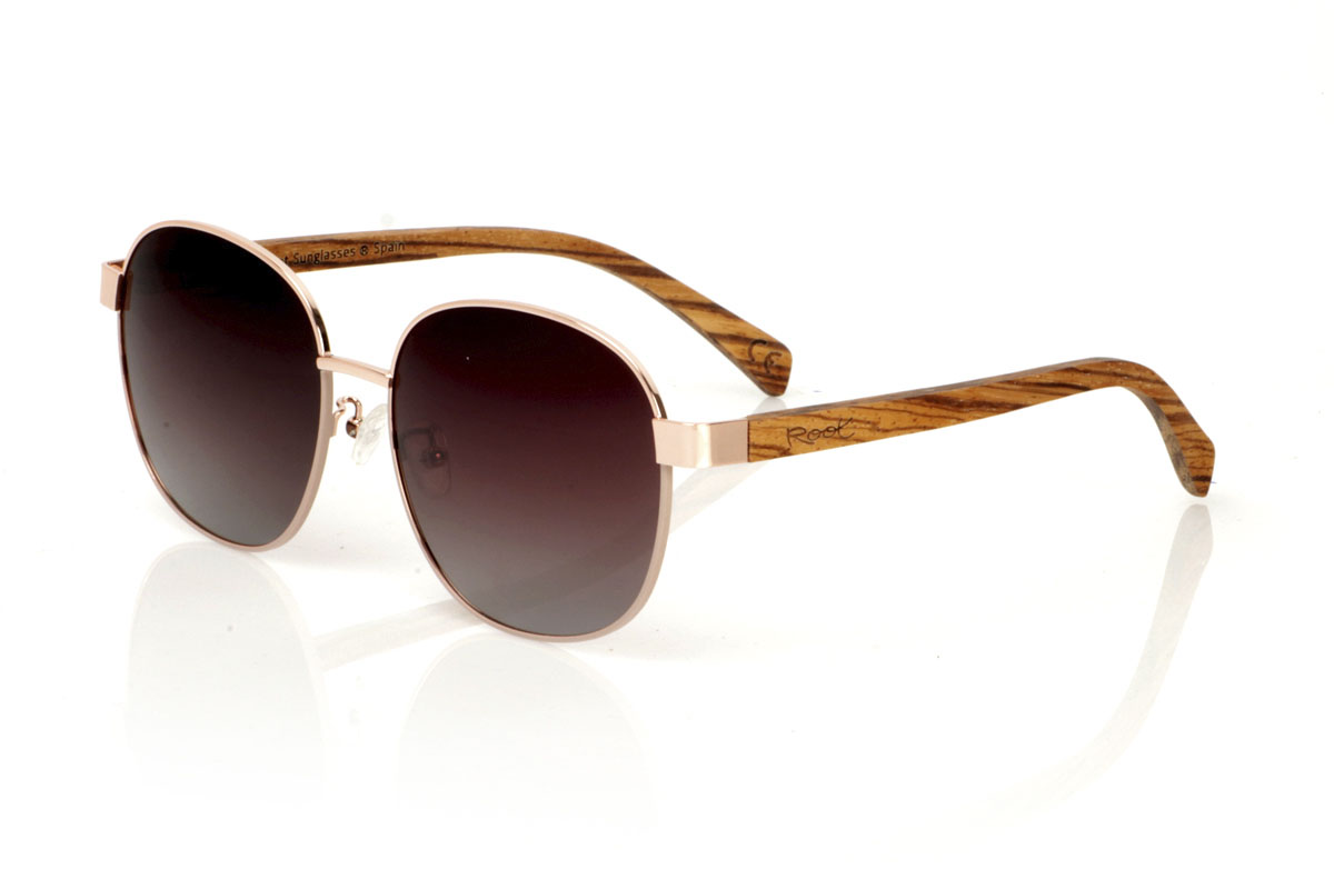 Wood eyewear of Zebrano modelo CHLOE. CHLOE sunglasses are the definition of versatility and timeless style. This unisex model fuses a thin metal frame in bronze, evoking a vintage touch, with zebra wood temples that add a natural and modern contrast. The combination results in glasses that adapt to both classic and contemporary looks, perfect for anyone who appreciates elegance and quality. Measuring 156x54mm and with a caliber of 58, the CHLOE offers a comfortable fit and ample visual protection. Get ready to stand out with this unique design, which promises to become a must-have in your collection. | Root Sunglasses® 